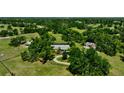 Aerial view showcasing the house, outbuildings, surrounding greenery, and a circular driveway at 6540 Prairie Junction Trl, Sarasota, FL 34241