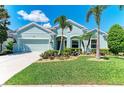 Inviting single-Gathering home featuring vibrant landscaping with flowers, palm trees, and a neatly kept green lawn at 736 Rosemary Cir, Bradenton, FL 34212