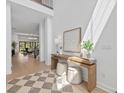 Sunlit foyer with soaring ceilings, wood floors, stylish console table and decor and views of the living room at 7765 Grande Shores Dr, Sarasota, FL 34240