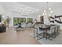 Open concept living room and dining area with coffered ceilings, hardwood floors and large windows at 7765 Grande Shores Dr, Sarasota, FL 34240