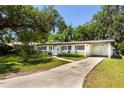 Inviting single-story home with a long driveway, well-kept lawn, and lush landscaping at 1005 Powell St, Plant City, FL 33563