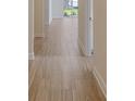Hallway with wood-look tile floors leading to a doorway and window to the lanai at 12570 Brookgreen St, Venice, FL 34293