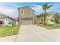 Two story home featuring a two-car garage, neutral stucco, manicured lawn and tropical landscaping with palm trees at 1912 Hawks View Dr, Ruskin, FL 33570
