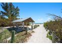Picturesque beach access path leading to a serene sandy beach with a shaded pavilion at 204 75Th St, Holmes Beach, FL 34217