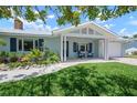 Single-story home with light blue siding, dark shutters, manicured landscaping, and covered porch at 204 75Th St, Holmes Beach, FL 34217