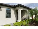 Charming home entrance featuring a covered porch, well-maintained landscaping, and a cozy seating area at 2193 Bonito Way, Port Charlotte, FL 33953