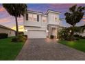 Gorgeous two-story home with stone facade, a paved driveway, and nicely landscaped lawn with mature palm trees at 3210 Desert Plain Cv, Lakewood Ranch, FL 34211
