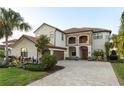 Beautiful two-story home featuring a balcony, stone accents, a brick driveway, and manicured landscaping at 5609 Arnie Loop, Lakewood Ranch, FL 34211