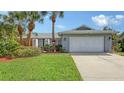 Well-maintained home featuring a lush front yard, mature palm trees, and a spacious two-car garage at 6583 Waterford Cir, Sarasota, FL 34238