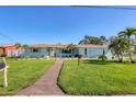 Inviting single-story home featuring a lush green lawn, decorative shutters, and mature landscaping at 10304 Sandpiper W Rd, Bradenton, FL 34209