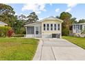 Welcoming yellow home featuring a screen porch, well-manicured lawn, and a paved driveway at 182 Crown Point Dr, Nokomis, FL 34275