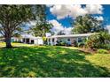 Landscaped front yard showcasing a charming home with mature trees, green lawn, and colorful plants at 2238 Rose St, Sarasota, FL 34239