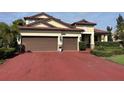 Beautiful home with a two-car garage, red brick driveway, and manicured green landscaping at 4622 Grand Lakeside Dr, Palm Harbor, FL 34684