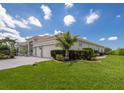 A well-maintained property featuring lush green lawns, manicured hedges, and a three-car garage, all under a clear blue sky at 7031 Scrub Jay Dr, Sarasota, FL 34241