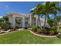 Beautifully landscaped home exterior featuring mature palm trees and a well-manicured lawn with decorative shrubbery at 7031 Scrub Jay Dr, Sarasota, FL 34241