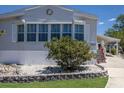 Charming home with manicured landscaping, a stone-lined garden, and covered porch at 8225 Drew St, Englewood, FL 34224