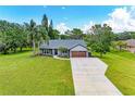 Well-maintained home with a long concrete driveway and lush lawn and tropical trees at 1103 134Th E St, Bradenton, FL 34212
