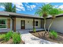 Inviting front porch with stone pathway, decorative columns, and beautifully landscaped greenery at 1103 134Th E St, Bradenton, FL 34212