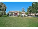 Inviting single-story home with a well-manicured lawn, tropical plants, and a vibrant red front door at 2183 Muskogee Trl, Nokomis, FL 34275