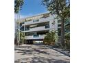 Stunning multi-level building with blue railings, lush greenery, and ocean views from the covered parking area at 340 Gulf Of Mexico Dr # 124, Longboat Key, FL 34228
