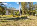 A simple home featuring minimal landscaping, a modest lawn, and mature shade trees at 440 Redwood Rd, Venice, FL 34293