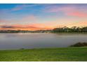 Scenic lake view at sunset with colorful skies and lush green landscape, perfect for serene living at 7743 Ridgelake Cir, Bradenton, FL 34203