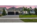 Charming home with a well-manicured lawn, stone accents, a three-car garage, and beautiful tropical landscaping at 8033 Grande Shores Dr, Sarasota, FL 34240