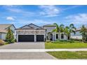 Charming home with a well-manicured lawn, stone accents, a three-car garage, and tropical landscaping at 8033 Grande Shores Dr, Sarasota, FL 34240