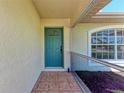 Entrance featuring a teal-colored front door complemented by tiled flooring and a storm door at 1323 Arredondo St, North Port, FL 34286