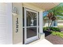 Close-up of the decorative storm door featuring a palm tree design with fresh landscaping at 1323 Arredondo St, North Port, FL 34286