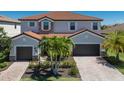 Charming home with a red tile roof, lush landscaping, and a paver driveway leading to a spacious two-car garage at 13409 Ramblewood Trl, Bradenton, FL 34211