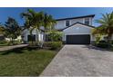 Inviting two-story home with a two-car garage, paver driveway, lush landscaping and palm trees enhances curb appeal at 13409 Ramblewood Trl, Bradenton, FL 34211