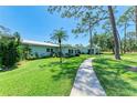 Beautiful home featuring a lush green lawn and sidewalk leading to the front door, with palm tree and mature landscaping at 1622 Stafford Ln # 1205, Sarasota, FL 34232