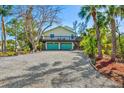 Inviting two-story home featuring a spacious deck, lush tropical landscaping, and an expansive driveway at 234 85Th St, Holmes Beach, FL 34217