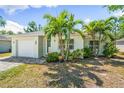 Charming single-story home featuring a well-maintained lawn, palm trees, and a brick driveway leading to an attached garage at 2840 S Shade Ave, Sarasota, FL 34239