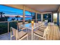 Relaxing screened patio area with stylish white furniture and expansive ocean views at sunset at 3201 Casey Key Rd, Nokomis, FL 34275