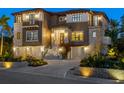 Beautiful home exterior with a three-car garage and manicured landscaping lit up at night at 3465 Gulfmead Dr, Sarasota, FL 34242