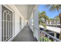 Exterior walkway showing unit doors and railings, with a glimpse of the carport and tropical palm trees at 4380 Exeter Dr # H202, Longboat Key, FL 34228
