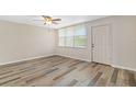Open-concept living room featuring modern laminate flooring, a ceiling fan, and a storm door with windows at 4885 1St Ne St # 308, St Petersburg, FL 33703