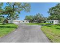 Long driveway to modern home with guest house surrounded by mature trees and green lawn at 7200 Chameleon Way, Sarasota, FL 34241