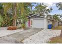 Charming home showcasing a cute pink door, a white garage, and a well-maintained landscaped yard at 7795 Wright Ave, Sarasota, FL 34231