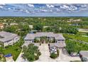 Aerial view of condo buildings with tile roofs, pond views, mature trees and ample parking at 902 Addington Ct # 202, Venice, FL 34293