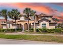 Stunning two-story home with lush landscaping and palm trees against the backdrop of a colorful sky at 141 Bella Vista Ter # 34D, Nokomis, FL 34275