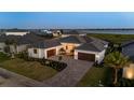 Stunning waterfront home features a manicured lawn, brick driveway, and three-car garage at 1613 4Th E St, Palmetto, FL 34221