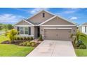 Well-maintained home with a two-car garage, verdant lawn, and thoughtfully designed landscaping for a welcoming feel at 16341 Little Garden Dr, Wimauma, FL 33598