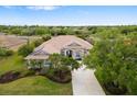 Aerial view of a tan single-story home featuring a tile roof, lush landscaping, and a long driveway in a wooded neighborhood at 244 Dove Trl, Bradenton, FL 34212