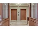 Grand entrance to private elevators with classic wood doors and marble flooring, creating a luxurious arrival at 464 Golden Gate Pt # 702, Sarasota, FL 34236