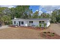 A charming white single-story home is enhanced by a lush front lawn and thoughtful landscaping at 4823 Linwood St, Sarasota, FL 34232