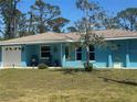Charming blue single-story home featuring a well-maintained lawn, inviting facade, and pristine white trim at 534 Lewis St, Englewood, FL 34223