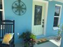 Charming home entrance with a decorative compass rose, welcome mat, and lush potted plants, plus a rocking chair at 534 Lewis St, Englewood, FL 34223